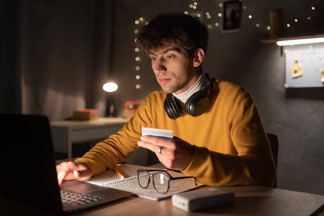 A male college student up at night making an online purchase.